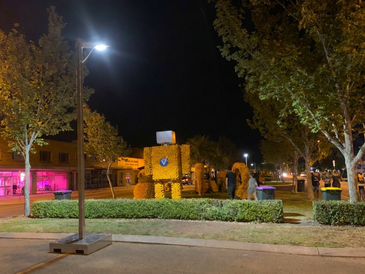 a mobile solar lighting tower lighting a street near a park